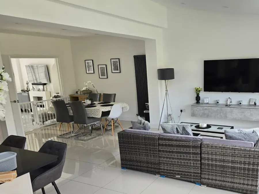 An open-plan living and dining space under a roof lantern, completed by GS Renovation